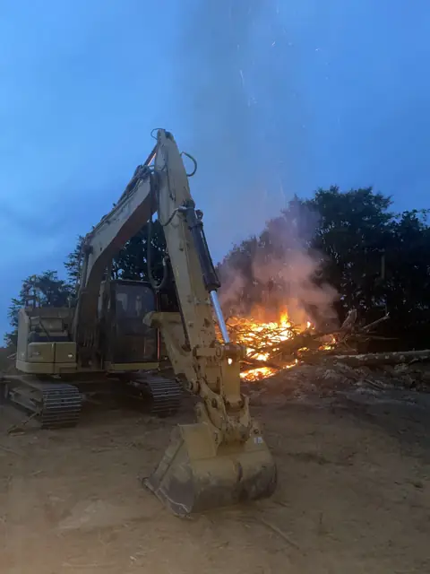 Excavator tending a brush fire after clearing