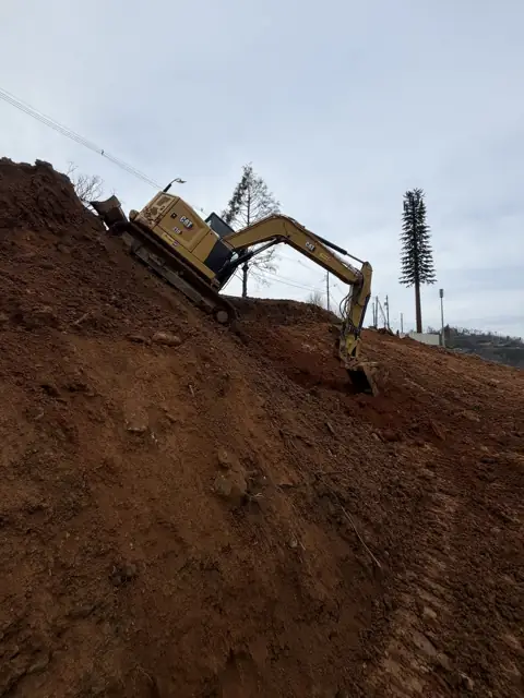 Excavator working on a hillside lot