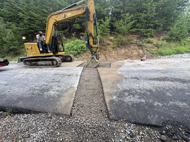 Excavator cutting a trench through asphalt