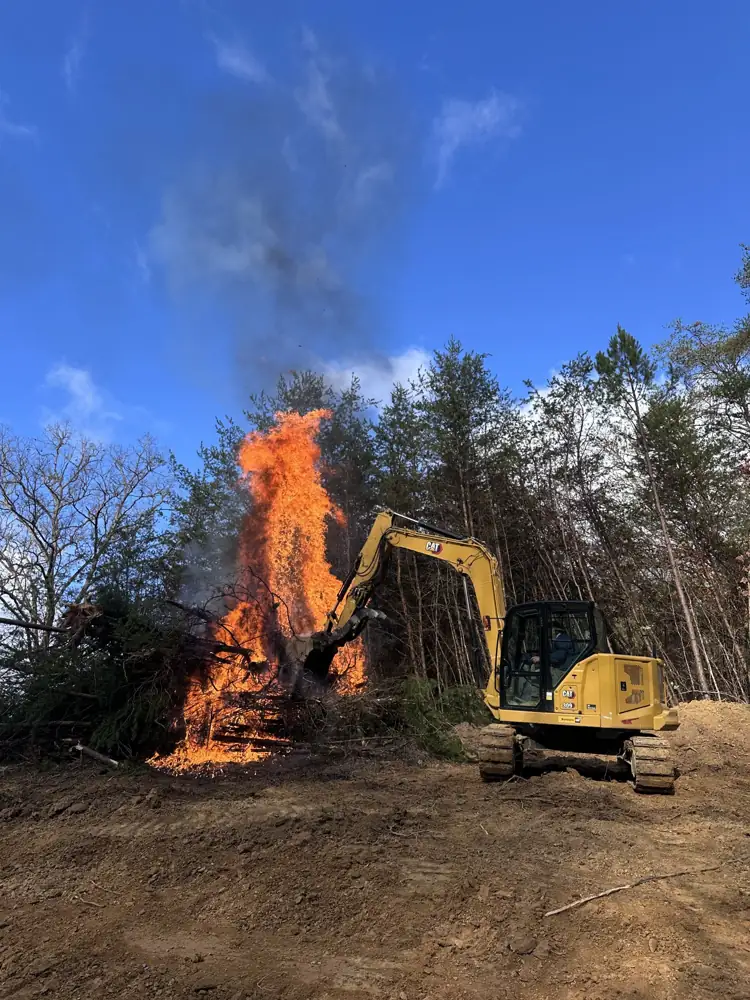 Brush pile burning while an excavator clears a lot in East Tennessee
